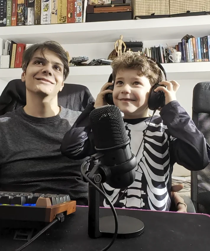 Father and son at a microphone with headphones on, recording voices for the game